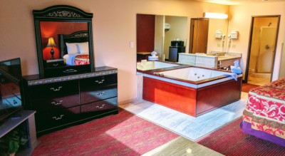 Executive Whirlpool Suite at Grand Marquis Hotel in Wisconsin Dells - corner view of room from window with whirlpool, dresser, vanity, and partial view of bed and tv