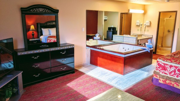 Executive Whirlpool Suite at Grand Marquis Hotel in Wisconsin Dells - corner view of room from window with whirlpool, dresser, vanity, and partial view of bed and tv